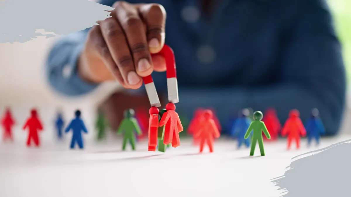 A hand using a magnet to attract colorful figurines, symbolizing customer attraction through PR and digital marketing strategies.