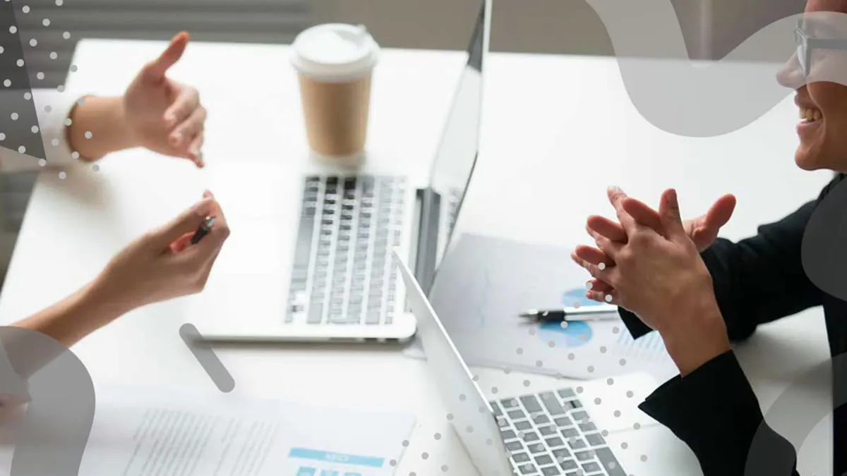 Two professionals having a discussion at a desk with laptops and documents, symbolizing effective public relations strategies.