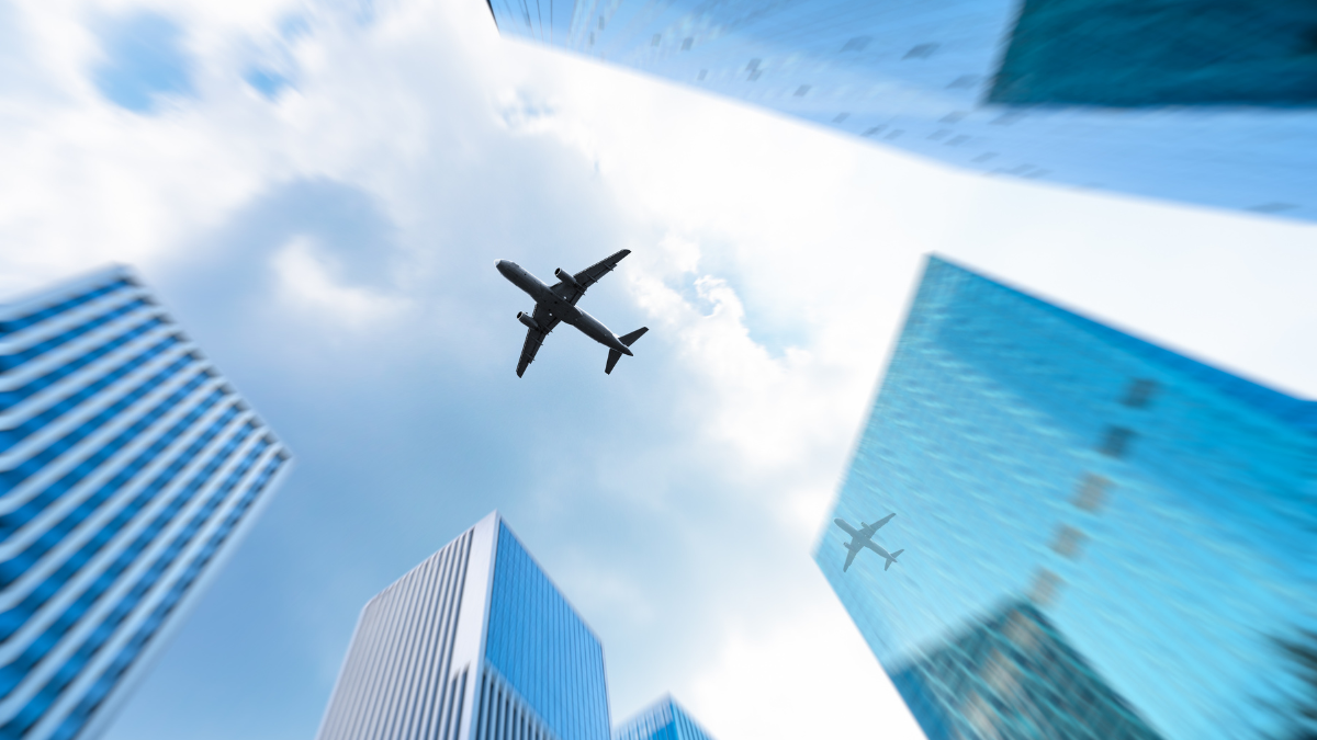 Innovación tecnológica y conectividad en la aviación moderna. Avión comercial sobrevolando un distrito financiero con rascacielos de cristal, simbolizando la conexión global y la innovación tecnológica en la industria de la aviación.